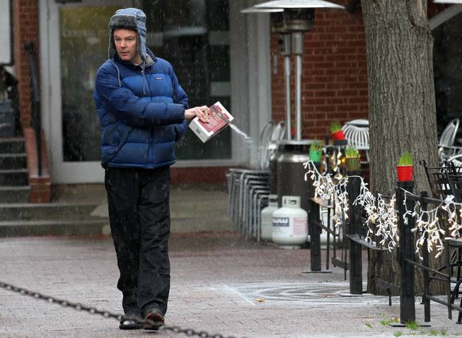 Brian Helleberg, owner of Petit Pois Restaurant, sprinkles salt around the patio as freezing rain falls on Sunday, Dec. 8, 2013 in downtown Charlottesville, Va. A mix of freezing rain, sleet and snow is delivering a sloppy winter smorgasbord from the Mid-Atlantic through southeastern Pennsylvania and northern New Jersey. (AP Photo/The Daily Progress, Ryan M. Kelly)